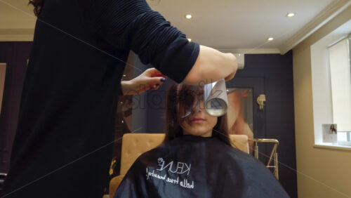 Video - Chisinau, Moldova - April 15, 2021: Hairdresser wearing mask styling woman's hair at the salon