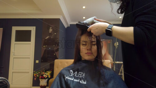 Video - Chisinau, Moldova - April 15, 2021: Hairdresser wearing mask styling woman's hair at the salon