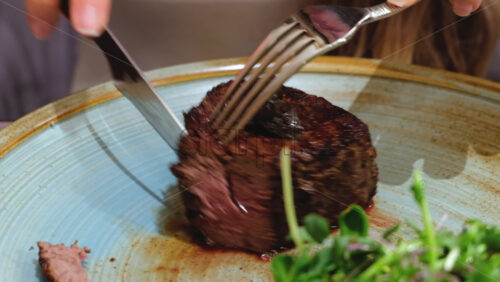 Video - Close up of a woman cutting a piece of filet mignon at a restaurant