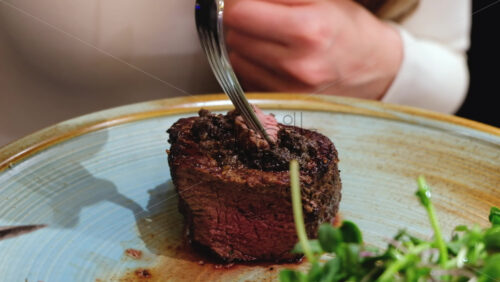 Video - Close up of a woman cutting a piece of filet mignon at a restaurant
