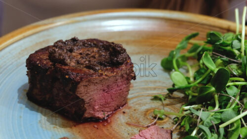 Video - Close up of a woman cutting a piece of filet mignon at a restaurant
