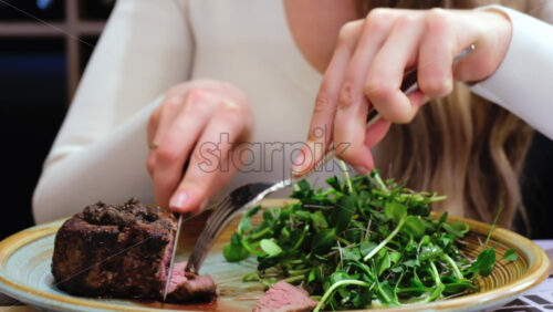 Video - Close up of a woman cutting a piece of filet mignon at a restaurant