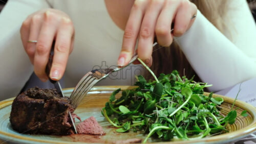 Video - Close up of a woman cutting a piece of filet mignon at a restaurant