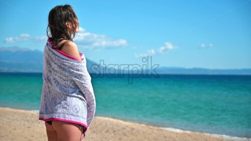 Video - Caucasian woman wrapped in a towel in swimsuit on a beach in slow motion, Asprovalta, Greece