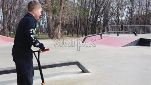 Video - Chisinau, Moldova - April 20, 2021: Boys moving on kick scooters in a skate park