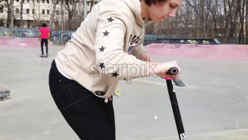 Video - Chisinau, Moldova - April 20, 2021: Boy doing tricks on kick scooter in a skate park