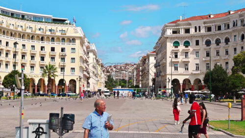 Video - THESSALONIKI, GREECE - SEPTEMBER 21, 2020:  Electra Palace Hotel viewed en face, colorfully dressed tourists walking