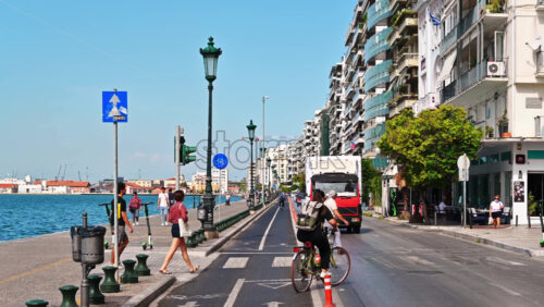 Video - THESSALONIKI, GREECE - SEPTEMBER 21, 2020: City downtown with car traffic and people riding bikes, jogging. Thessaloniki, Greece