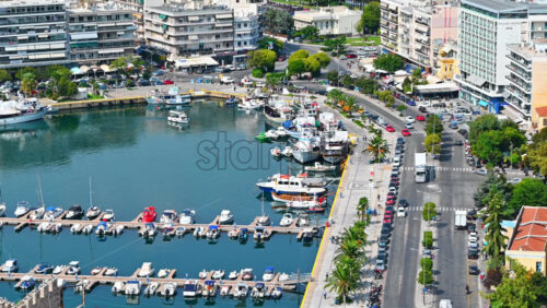 Video - KAVALA, GREECE - SEPTEMBER 23, 2020: Aerial view of the city. Rows of residential buildings, Aegean sea port with moored yachts, roads with people and cars