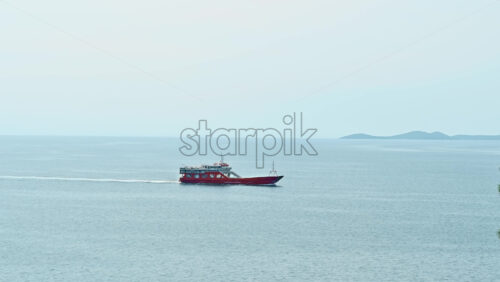 Video - KAVALA, GREECE - SEPTEMBER 23, 2020: Moving red ship near the Aegean sea coast, land on the background