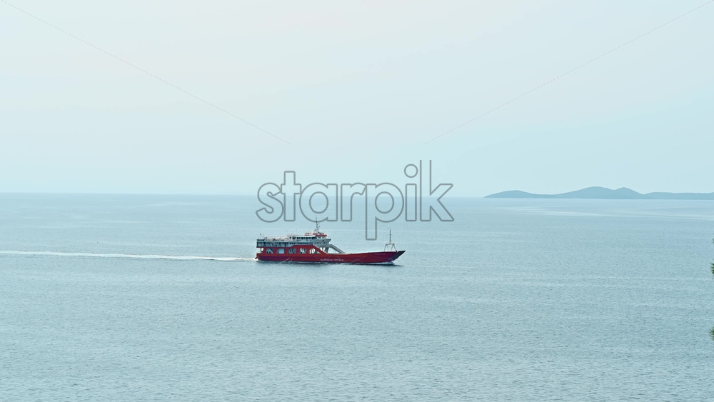 Video - KAVALA, GREECE - SEPTEMBER 23, 2020: Moving red ship near the Aegean sea coast, land on the background