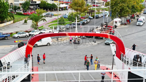 Video - THASOS, GREECE - SEPTEMBER 23, 2020: Moored ferryboat, opened gangplank in the port, road, walking people, town and parked cars on the background