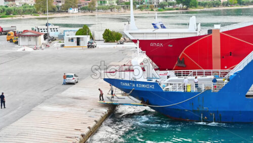 Video - THASOS, GREECE - SEPTEMBER 23, 2020: Moored ferryboats with blue and red exteriors, opened gangplanks in the port, people are walking out of the ship