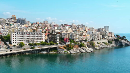 Video - KAVALA, GREECE - SEPTEMBER 23, 2020: Aerial view of the town. Rows of residential buildings, Aegean sea rocky coast, road with cars