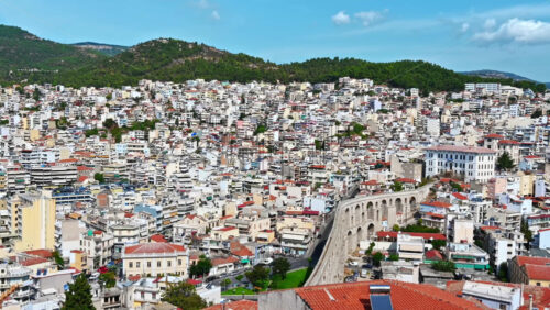 Video - KAVALA, GREECE - SEPTEMBER 23, 2020: Aerial view of the city. Rows of residential buildings , viaduct, roads, green hills on the background