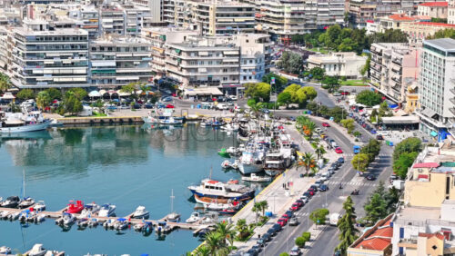 Video - KAVALA, GREECE - SEPTEMBER 23, 2020: Aerial view of the city. Rows of residential buildings, Aegean sea port with moored yachts, roads with people and cars