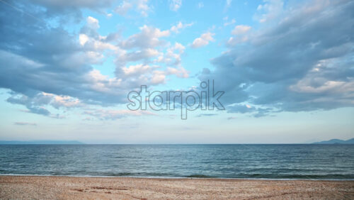 Video - A beach and Aegean sea, partly cloudy sky, hills in the distance, Greece