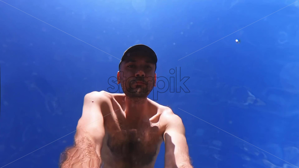 Video - Man shooting himself under the water of the Aegean sea. Slow motion, underwater shooting. Greece