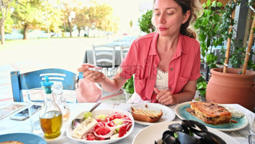 Video - A woman in a restaurant, eating, multiple dishes with mediterranean food on the street, Asprovalta, Greece