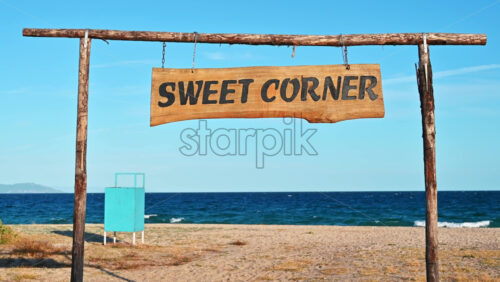 Video - Sweet Corner sign made of wood on the beach with Aegean sea on the background, Olympiada, Greece