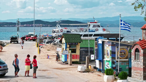 Video - OURANOUPOLIS, GREECE - OCTOBER 2, 2020: Sea port with moored boats, road to the pier with parked cars, people and booth for tickets