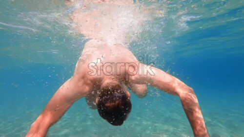 Video - Man in swimming goggles rotating under the water, Aegean sea. Slow motion, underwater shooting. Greece