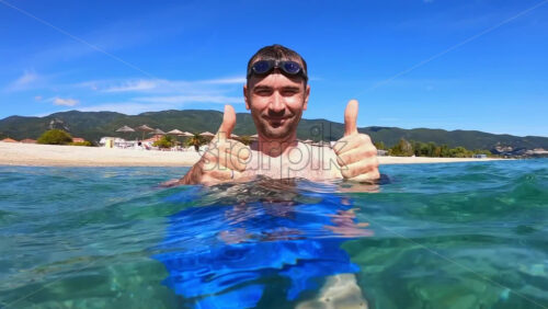 Video - Man showing like in the water of the Aegean sea, nature on the background. Slow motion. Greece
