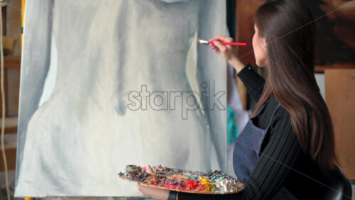 Video - Woman painter wearing black clothes painting woman model at a workshop