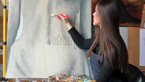 Video - Woman painter wearing black clothes painting woman model at a workshop