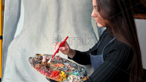 Video - Woman painter wearing black clothes painting woman model at a workshop