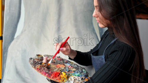 Video - Woman painter wearing black clothes painting woman model at a workshop