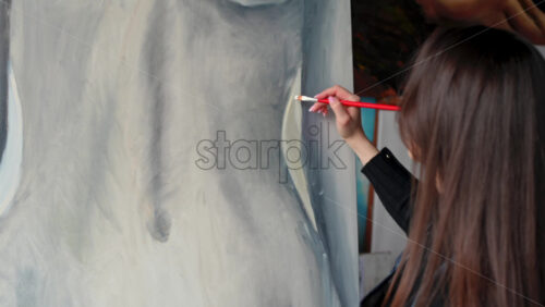 Video - Woman painting a female body on a canvas at an art gallery workshop