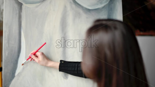 Video - Woman painter wearing black clothes painting woman model at a workshop
