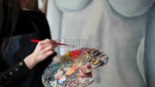 Video - Woman painter wearing black clothes painting woman model at a workshop