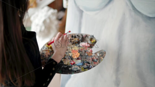 Video - Woman painter wearing black clothes painting woman model at a workshop