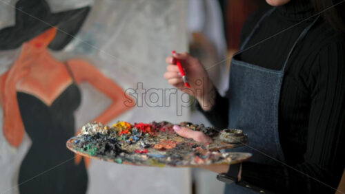 Video - Woman painting a female on a canvas at an art gallery workshop