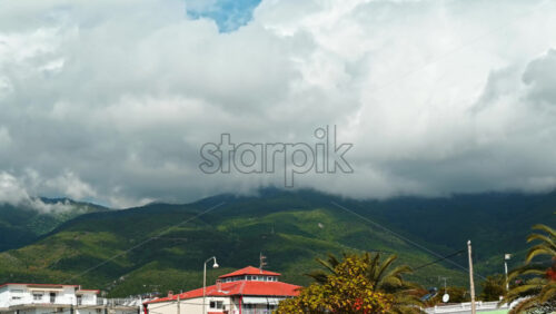 Video - Timelapse of a town and a mountain visible in the distance, moving clouds in Greece