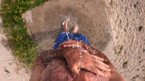 Video - A caucasian man taking shower on the beach. First-person view, slow motion