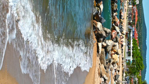 Video - NIKITI, GREECE - OCTOBER 5, 2020: Beach on Aegean sea coast, rocks in the water, embankment street, sea port and green hills in the distance