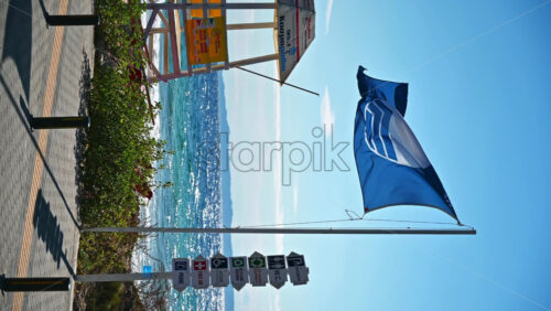 Video - NIKITI, GREECE - OCTOBER 8, 2020: Aegean sea coast with sign post, flag and first aid tower. Vertical shooting