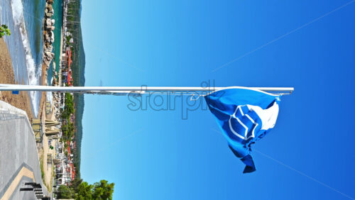 Video - A blue flag with a sign on it near the embankment street, greenery, Aegean sea cost in Nikiti, Greece. Vertical shooting