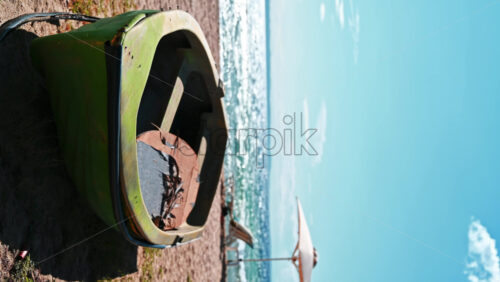 Video - Beached boat made of green colored metal, umbrellas, sunbeds and Aegean sea on the background in Nikiti, Greece. Vertical shooting