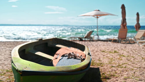 Video - Beached boat made of green colored metal, umbrellas, sunbeds and Aegean sea on the background in Nikiti, Greece