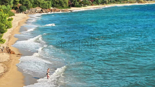 Video - NEOS MARMARAS, GREECE - OCTOBER 8, 2020: Aegean sea coast, rocky hills with growing trees and bushes, beach with waves and umbrellas with sunbeds