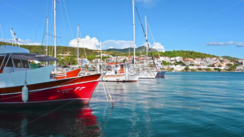 Video - NEOS MARMARAS, GREECE - OCTOBER 8, 2020: Aegean sea port with multiple moored yachts and boats, town located on a hill with greenery, clear weather