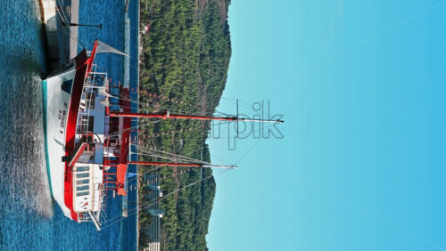 Video - NEOS MARMARAS, GREECE - OCTOBER 8, 2020: Moored sailboat near a pier, green hill on the background. Slow motion, vertical shooting