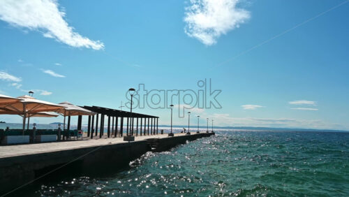 Video - Pier with cafe, umbrellas, gazebo and lamp posts, Aegean sea in Nikiti, Greece