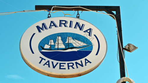 Video - NIKITI, GREECE - OCTOBER 8, 2020: Marina Taverna street sign on a post, blue sky on the background