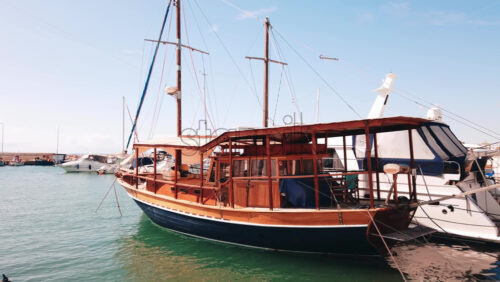 Video - Moored vintage sailboat in Aegean sea port, made of wood, yachts around. Slow motion