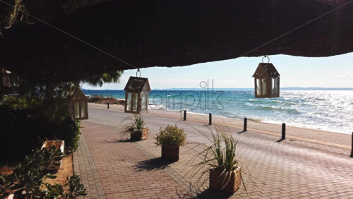 Video - Swaying in the wind cases for candles suspended by a tree branch, Aegean sea on the background in Nikiti, Greece. Slow motion
